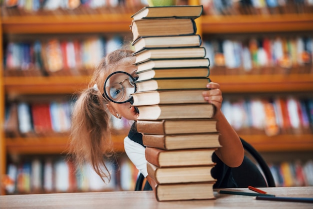 Niña linda con coletas está en la biblioteca