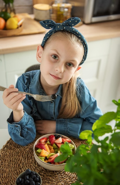 Niña linda come ensalada de frutas