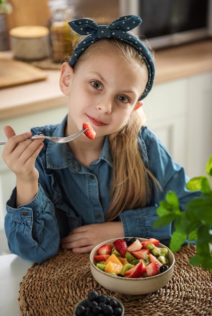 Niña linda come ensalada de frutas