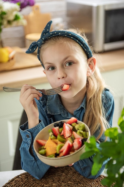 Niña linda come ensalada de frutas