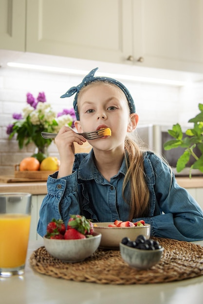 Niña linda come ensalada de frutas