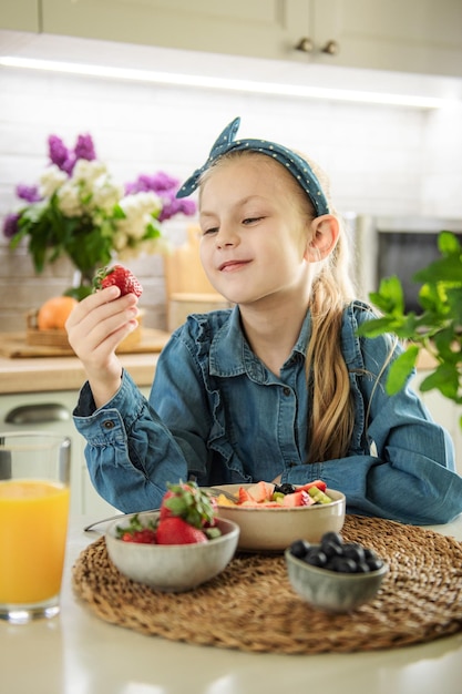 Niña linda come ensalada de frutas