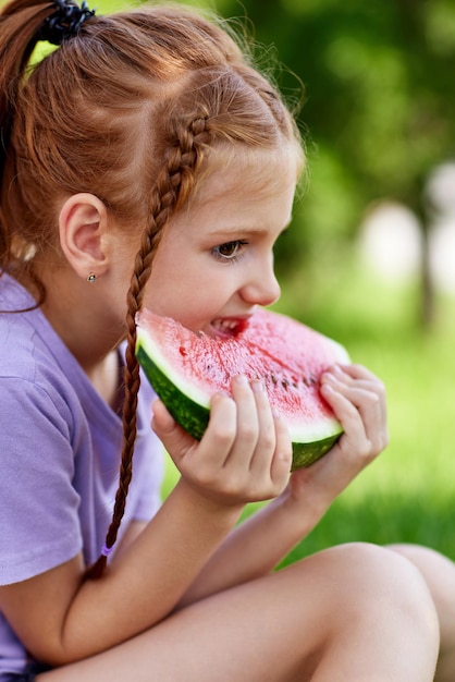 Niña linda come una sandía en un día soleado de verano