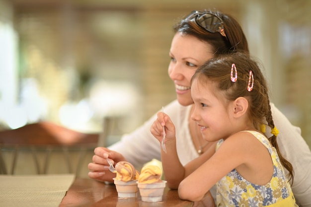 Niña linda comiendo helado con su madre