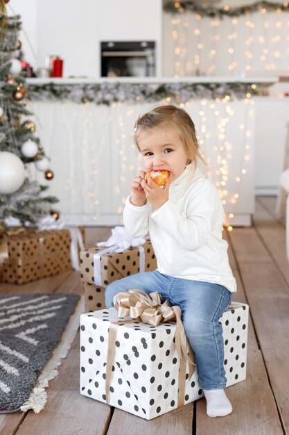 Niña linda comiendo mandarina en Navidad