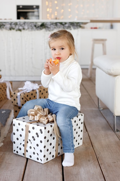 Niña linda comiendo mandarina en Navidad