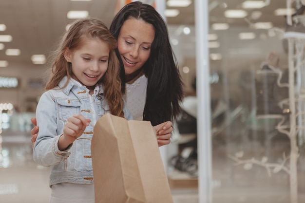 Niña linda de compras en el centro comercial con su madre