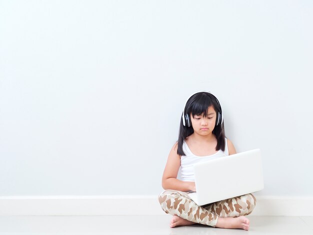 Niña linda con la computadora portátil en casa