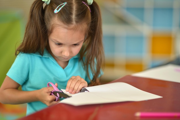 Foto la niña linda está cortando papel