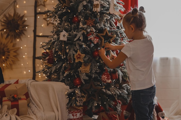 Niña linda decora un árbol de Navidad. Feliz Navidad y Año Nuevo.