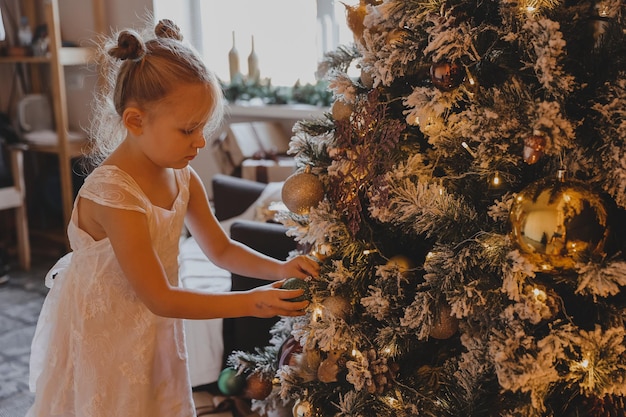 Niña linda decora un árbol de Navidad. Feliz Navidad y Año Nuevo.