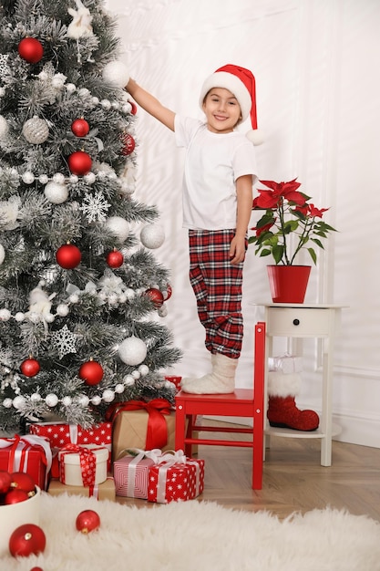 Niña linda decorar el árbol de navidad en casa