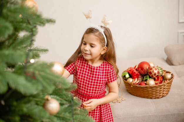 Niña linda decorar el árbol de navidad en casa