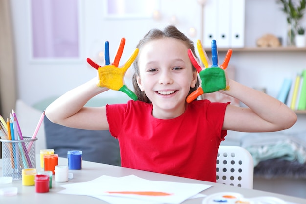 Niña linda dibuja pinturas en casa