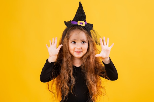 Niña linda en un disfraz de bruja de Halloween