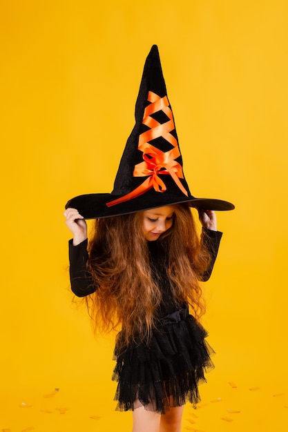 Niña linda en un disfraz de bruja de Halloween