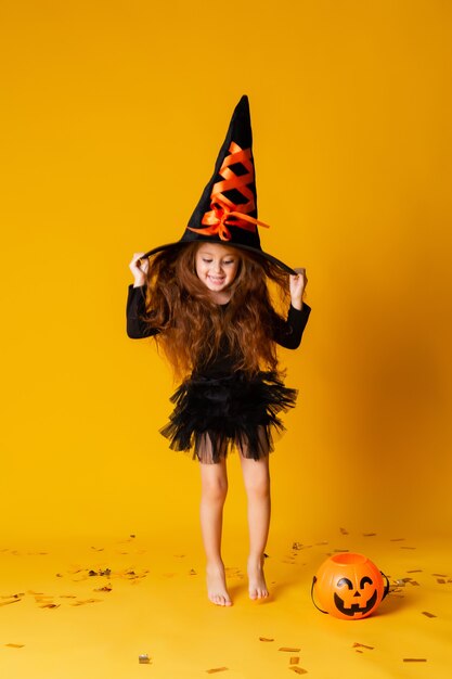 Niña linda en un disfraz de bruja de Halloween