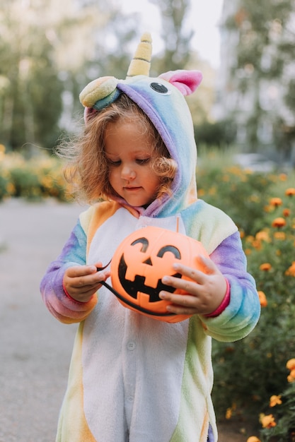 Niña linda con un disfraz de unicornio arcoíris para halloween va