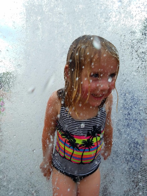 Foto una niña linda disfrutando de la fuente durante el verano