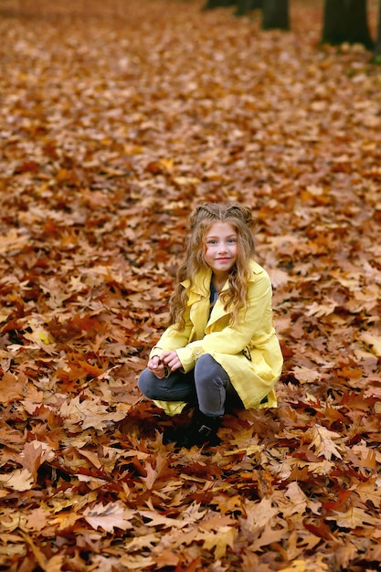 Niña linda divirtiéndose en el parque otoño.