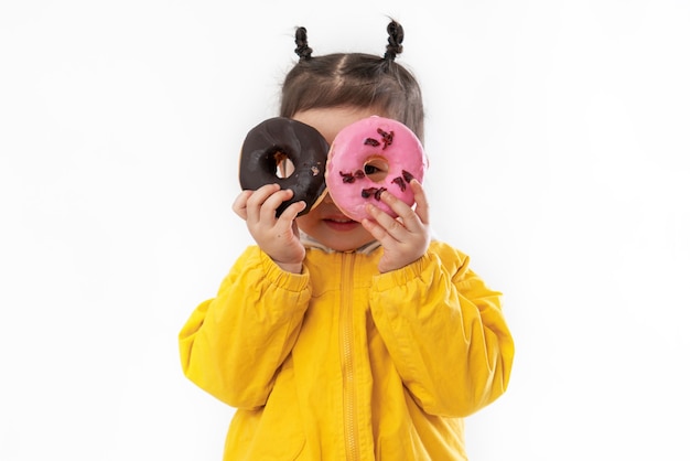 Niña linda con donas sobre un fondo blanco.