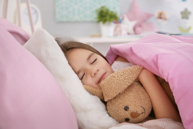 Niña linda durmiendo en la cama en casa