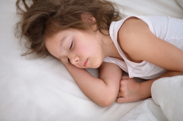 Niña linda durmiendo en una cama