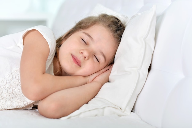 Niña linda durmiendo en una cama