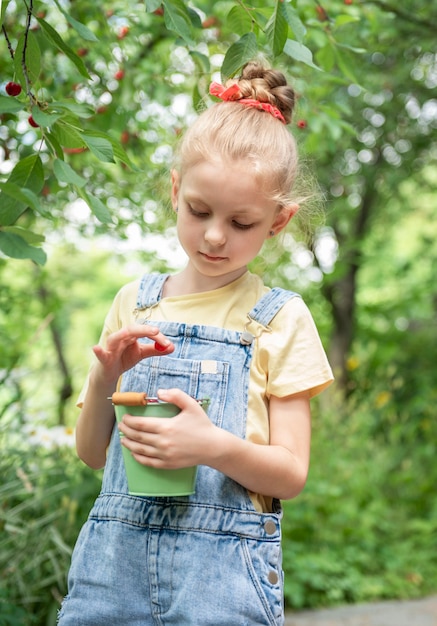 Niña linda escoge una cereza de un árbol en el jardín de cerezos