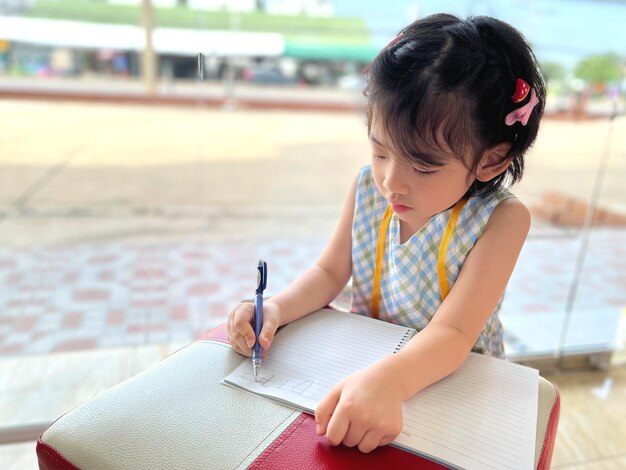 Foto niña linda escribe en su cuaderno