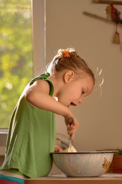 Niña linda está cocinando en la cocina. Disfruta haciendo galletas