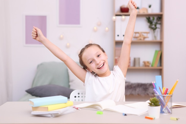 Niña linda está haciendo los deberes en el interior de la habitación