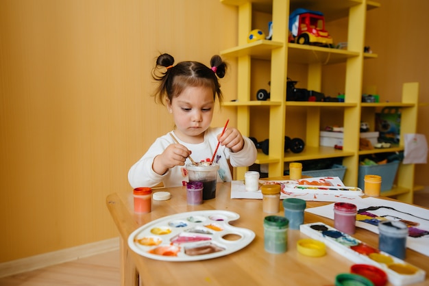 Una niña linda está jugando y pintando en su habitación. Recreación y entretenimiento.