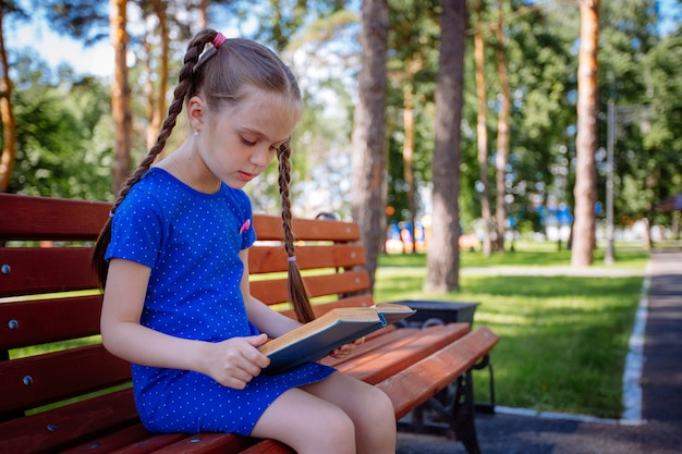 Niña linda está leyendo un libro al aire libre