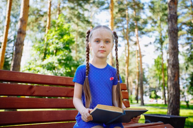 Niña linda está leyendo un libro al aire libre