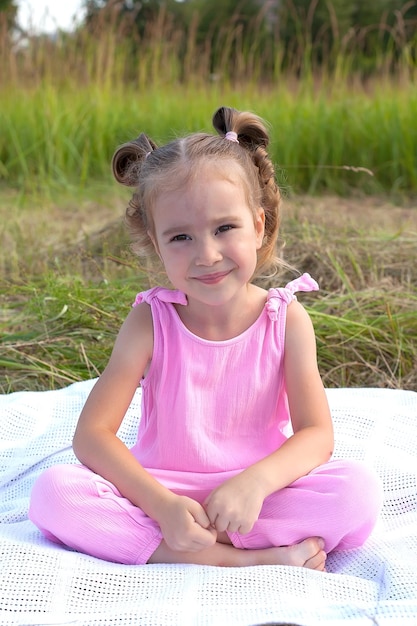 Una niña linda está sentada en la hierba en el campo Moda belleza Verano