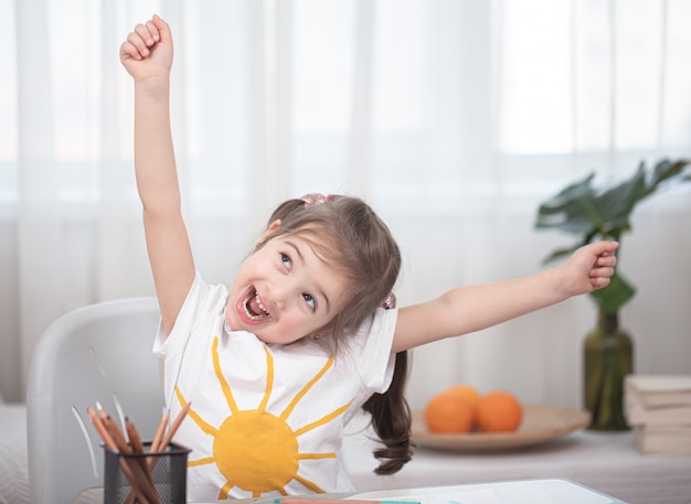 Una niña linda está sentada a la mesa y está haciendo sus deberes. Concepto de educación y educación en el hogar.