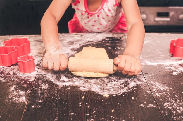 Niña linda estirando la masa en la cocina