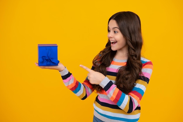 Niña linda felicita con el día de San Valentín dando una caja de regalo romántica Saludo actual y concepto de cumpleaños de regalo Adolescente feliz emociones positivas y sonrientes de niña adolescente