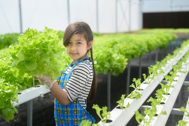 Una niña linda feliz aprendiendo y estudiando en la granja de invernadero hidropónico, la educación y el concepto científico