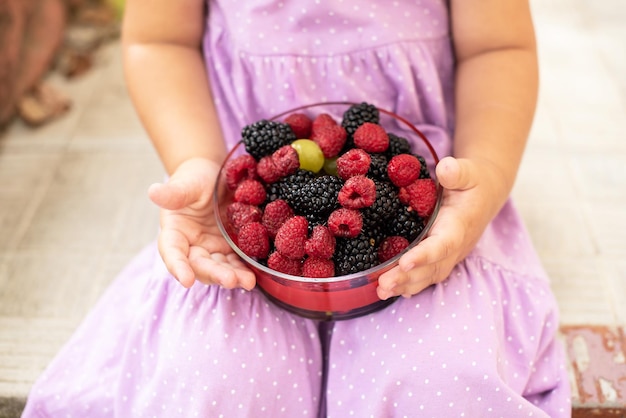 Niña linda feliz de comer frutas frambuesas y moras Comida deliciosa y saludable para niños