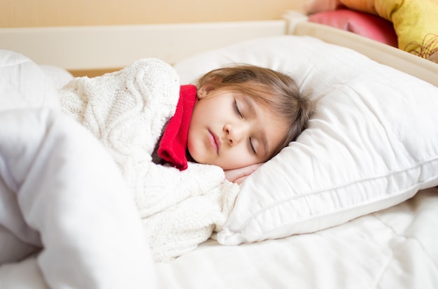 Niña linda con frío durmiendo debajo de la manta