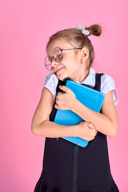 Niña linda con gafas y libros en espacio rosa, espacio para texto