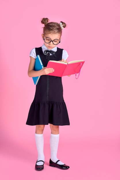 Niña linda con gafas y libros en espacio rosa, espacio para texto