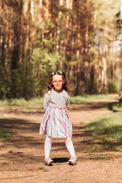 Una niña linda con gafas en la naturaleza en un día soleado