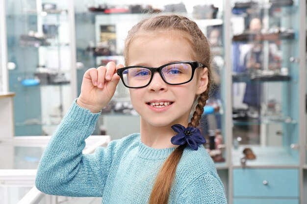 Niña linda con gafas nuevas en la tienda