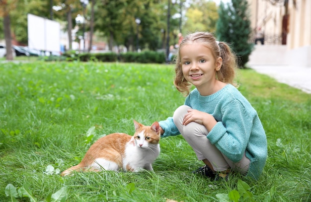 Niña linda con gato al aire libre