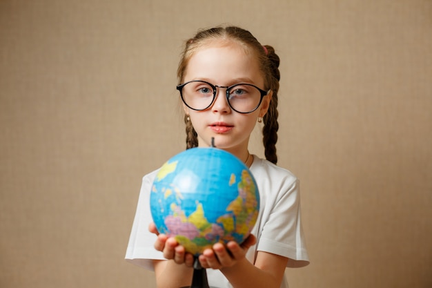 Niña linda con globo. Muchacha del niño con gafas en camiseta blanca. Concepto de educación escolar.