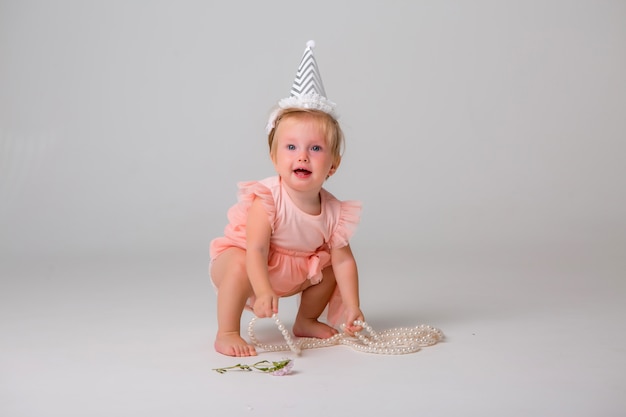 Niña linda en gorro de cumpleaños en luz