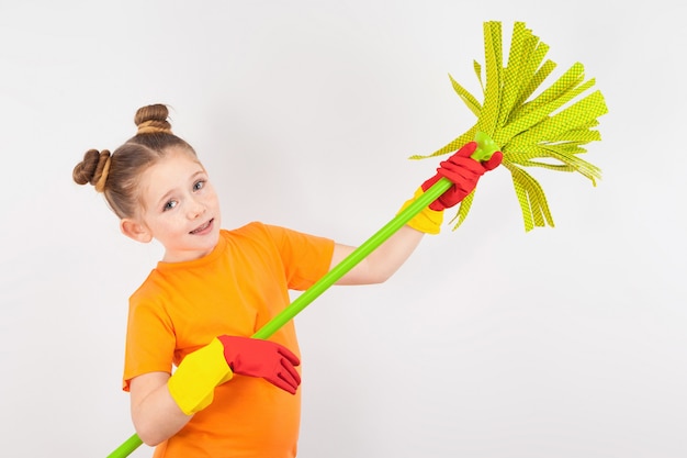 Niña linda en guantes con una escoba